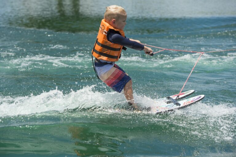 Child water skiing on double skis with properly fitted Coast Guard approved  life vest