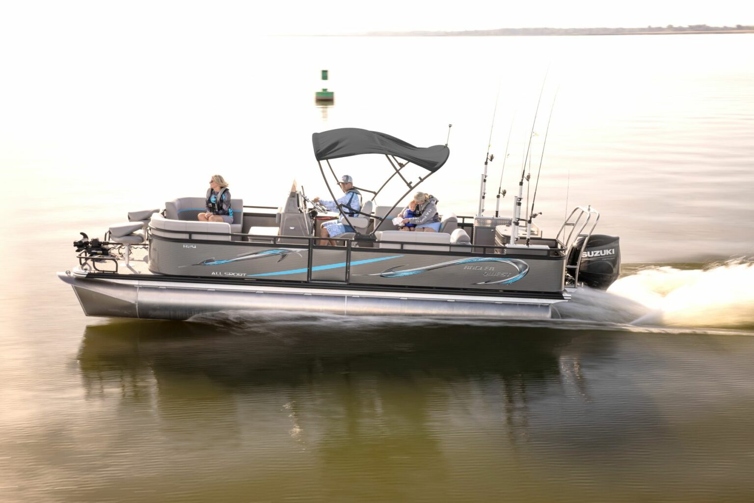 Royalty-free image - A silver pontoon boat with a canopy is speeding across calm water. Three people are on the boat, with two seated and one standing at the front. Fishing rods are visible, and the backdrop is a serene, expansive body of water with a green buoy.