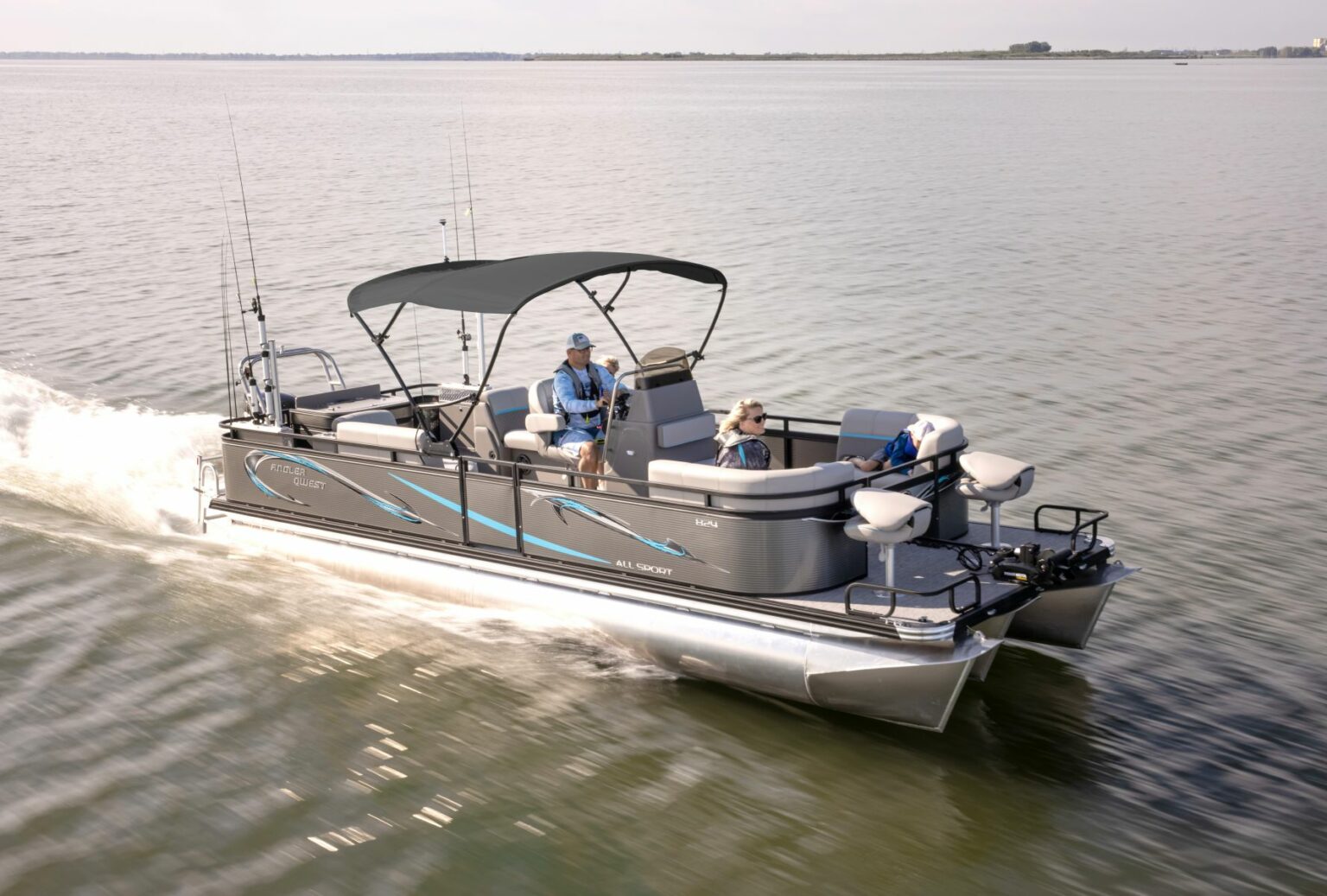 Royalty-free image - A pontoon boat with a canopy cruising on a calm lake. Two people are seated on the boat, enjoying the ride. The water reflects the boat&#039;s movement, and the shoreline is visible in the distance under a clear sky.