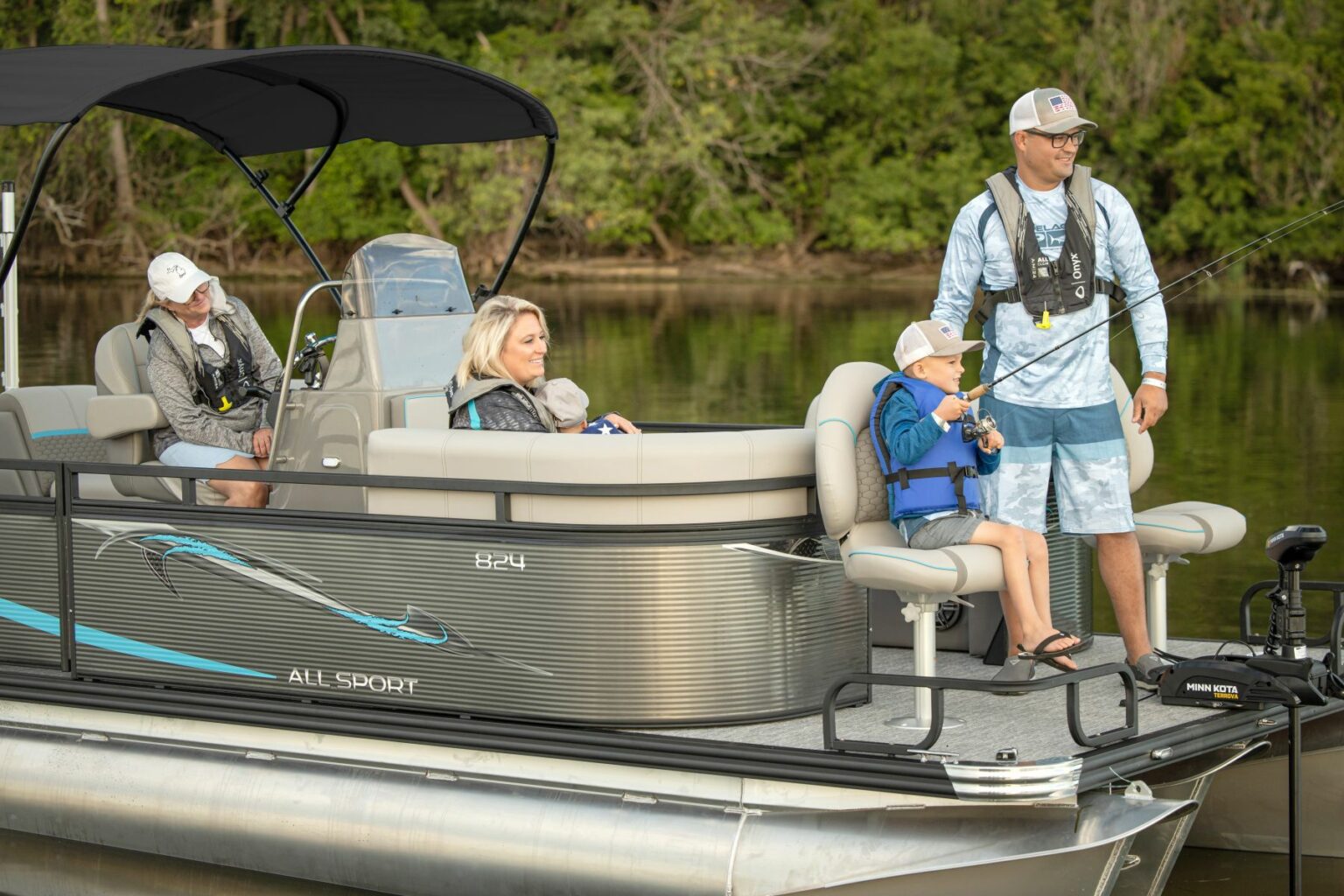 Royalty-free image - A family enjoys a day on a boat. A man stands fishing while a woman holds a child. An older man sits nearby, and a young child in a life vest is seated with a fishing rod. They are on a calm lake surrounded by trees.