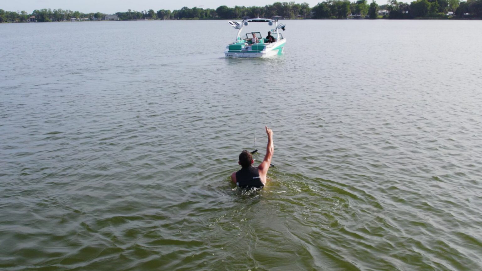 License-free image - Wakeboarder in water holding tow rope signaling &quot;Hit it&quot; to the ski boat captain off in the distance