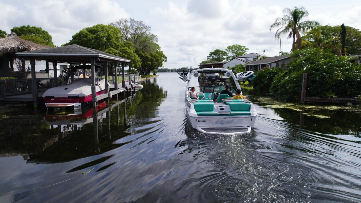 License-free image - Wake boat next to docks on a lake. Trees in the background