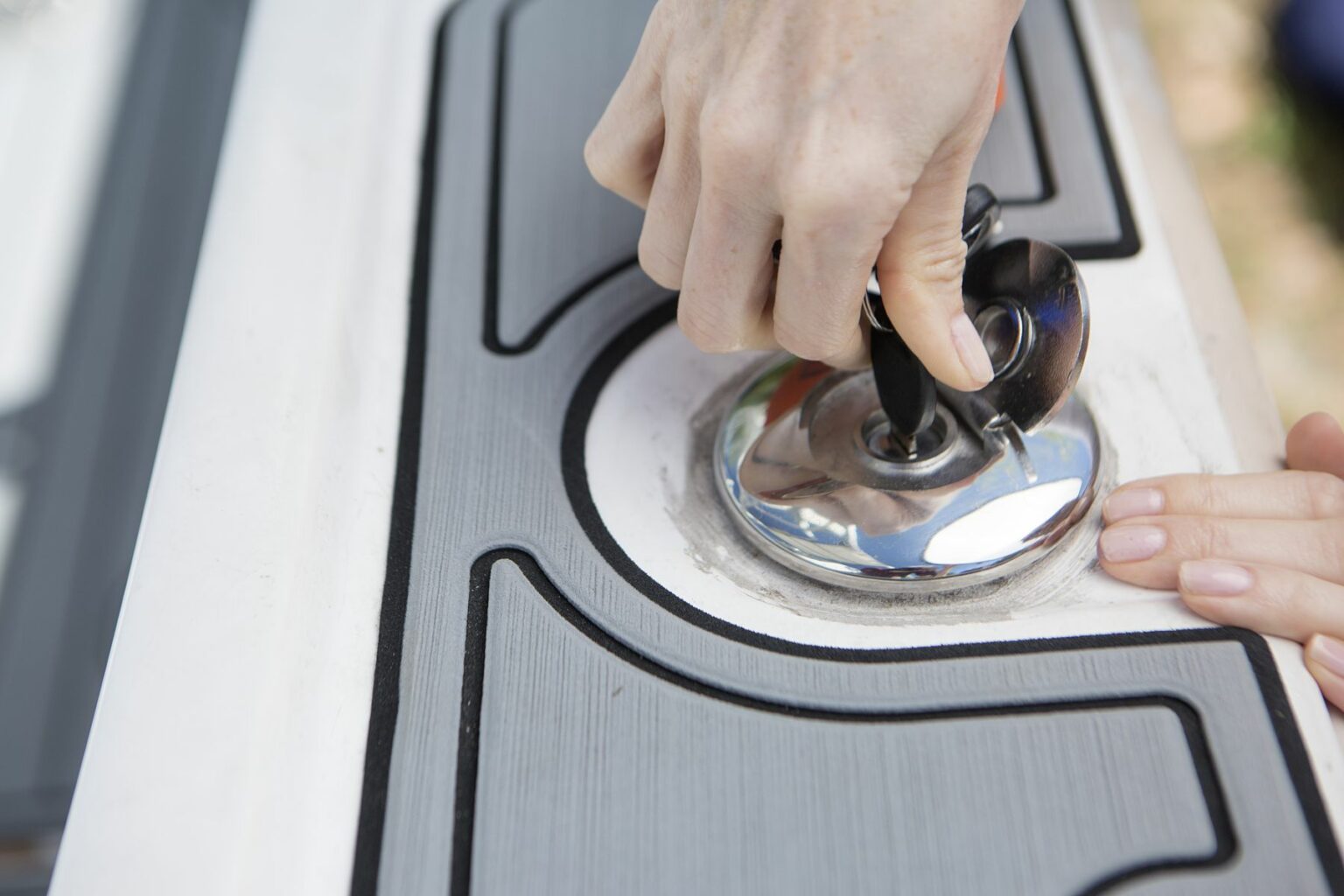 License-free image - Close-up of a person using a suction cup tool to install or repair a glass panel in a door. One hand is gripping the tool&#039;s handle and the other hand is steadying the panel. The image focuses on the hands, tool, and panel details. Opening a locked gas cap on a boat.