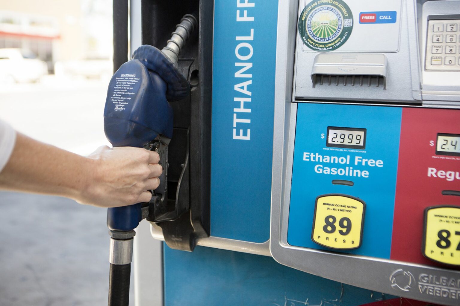 License-free image - A close-up of a person refueling a car at a gas pump labeled &quot;Ethanol Free Gasoline.&quot; The display shows a price of $2.999 per gallon and an octane rating of 89. The nozzle is blue, and the person&#039;s hand is gripping it while inserting it into the vehicle. Removing/replacing a nozzle from an ethanol free gas pump.