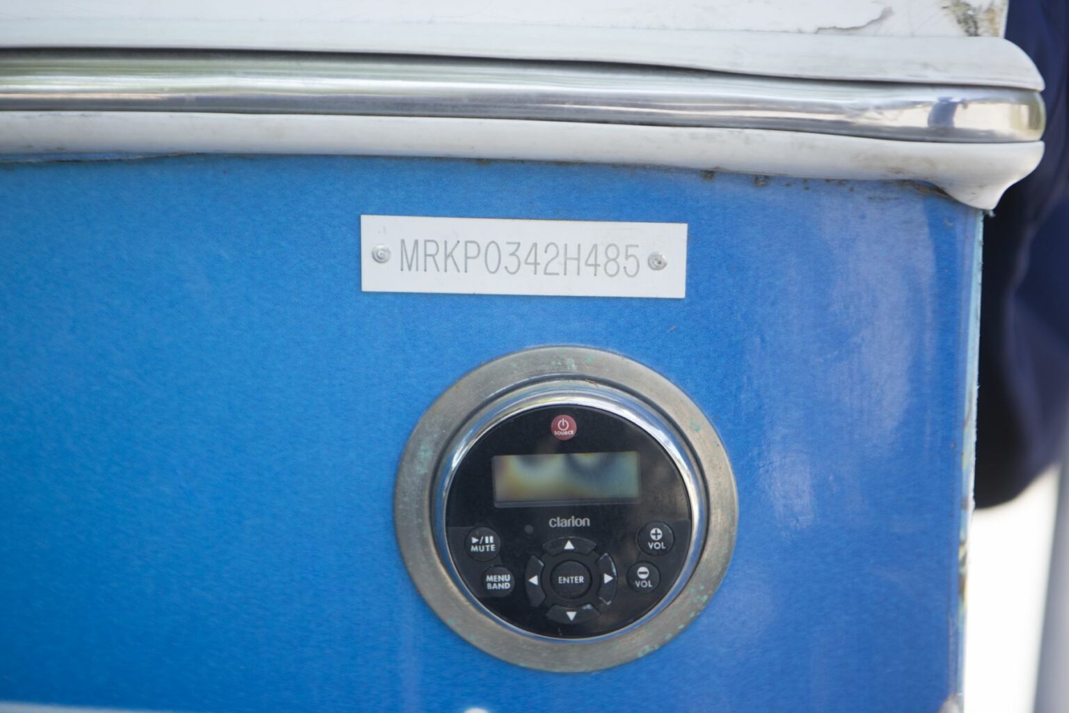 License-free image- Hull identification number on a watercraft.  Close-up of a blue boat&#039;s console featuring an identification plate with the code &quot;MRKP0342H485&quot; and a mounted Clarion stereo system with various buttons and a display screen.