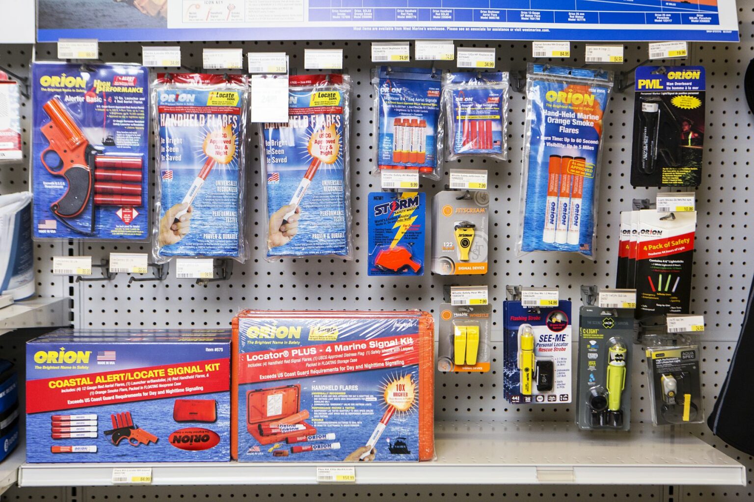 License-free image -  Store display featuring an assortment of emergency signal devices and safety equipment. Visible items include flares, signal lights, signal kits, and air horns from various brands, all arranged on a perforated display board with price tags. Flares and other safety equipment on the shelves at a retail outlet.