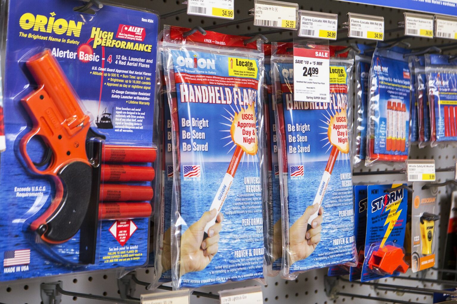 License-free image - A retail store display showing various safety flares and signaling devices. The products include packages labeled &quot;Orion Alert/Locate Handheld Flare,&quot; &quot;Alert/Locate Alerter Basic,&quot; and other safety kits. The display features bright packaging and price tags. Flares and other safety equipment on the shelves at a retail outlet.