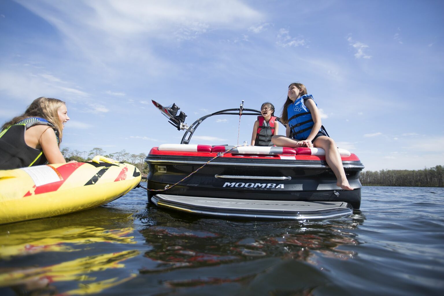 Kids having a fun afternoon on the water in properly fitting life jackets.