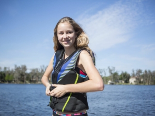 A girl zipping a life jacket for a day on the water.