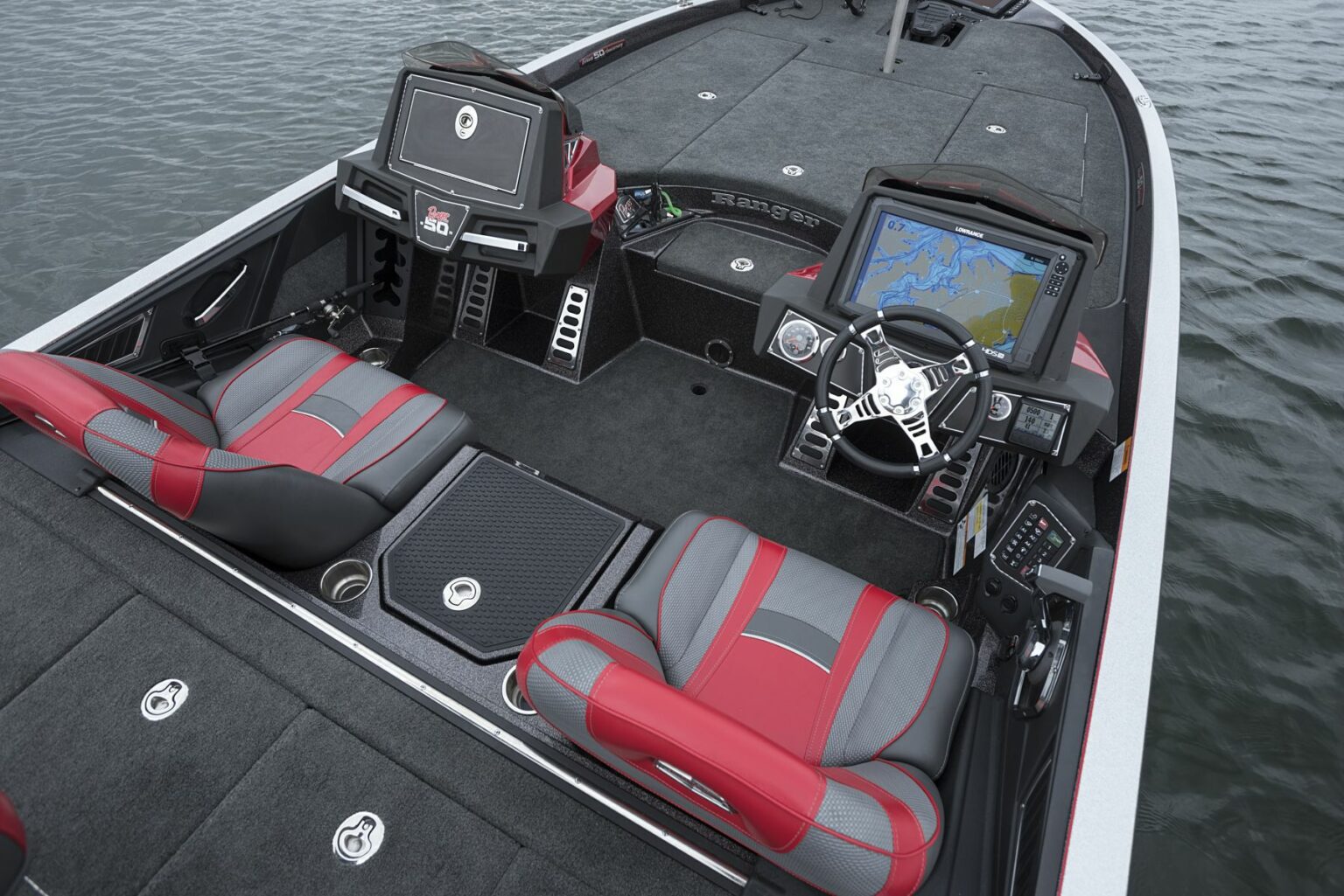 License-free image - The image shows the cockpit and seating area of a high-end fishing boat. The boat features two cushioned seats with red and grey upholstery, multiple control panels, a steering wheel, and a large touchscreen displaying a map. The boat is on a body of water. A deck free of hazards.