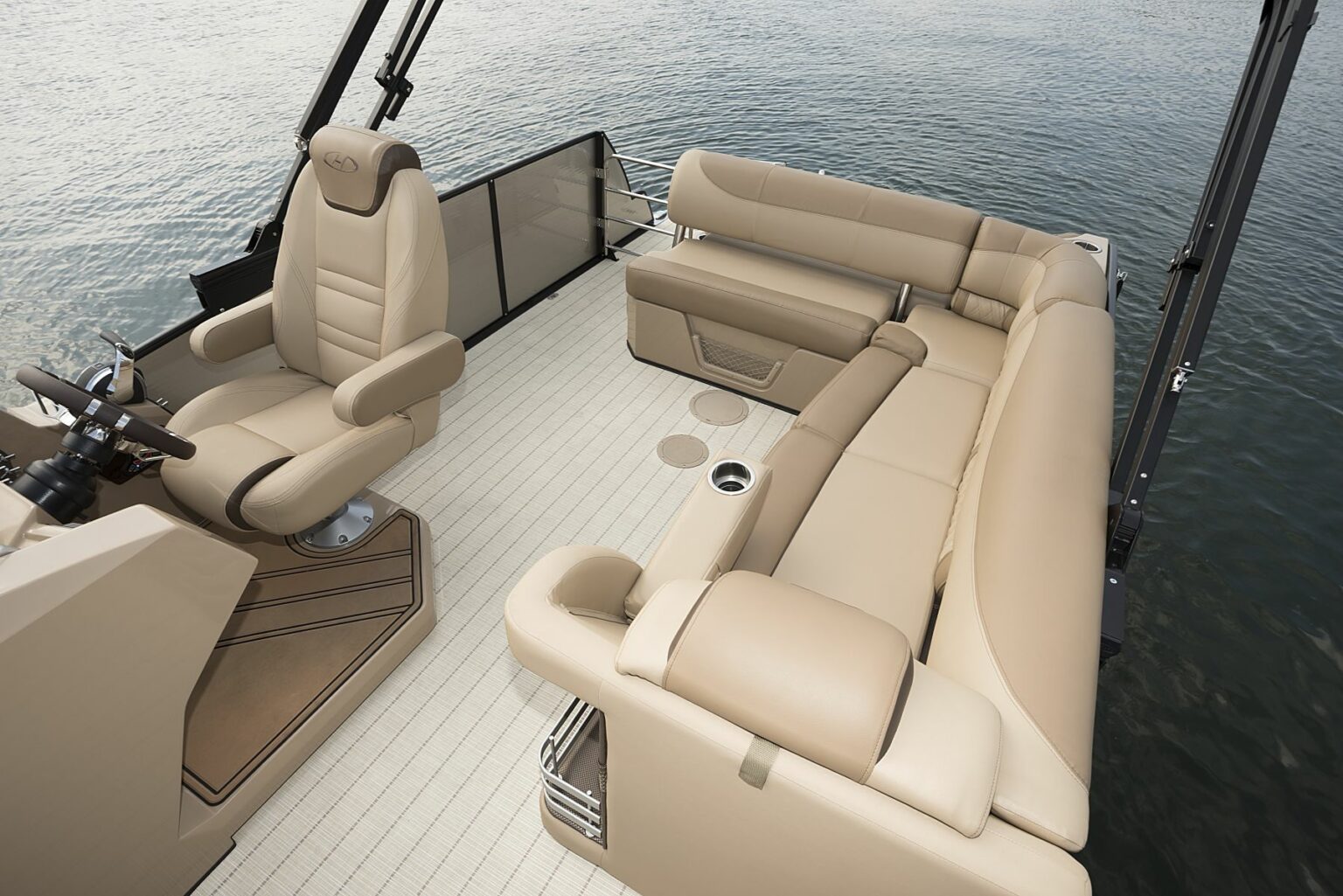 License-free image - A luxurious boat&#039;s seating area with beige leather seats. The arrangement includes a captain&#039;s chair with armrests, a corner sofa, and additional seating along the back, all set against a background of calm water. The deck features light-colored flooring. A deck free of hazards.